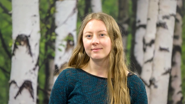 En kvinna står framför en målning med träd