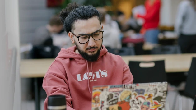 Studenten Nour pluggar med dator och anteckningsblock.