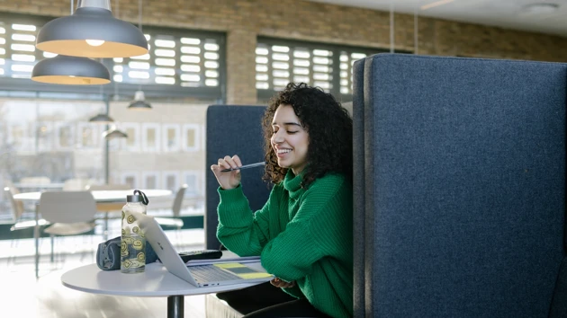 Studenten Sarah pluggar med dator och anteckningsblock.