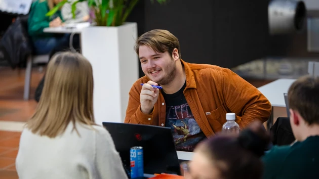 En glad student pluggar tillsammans med andra i Teknikhuset