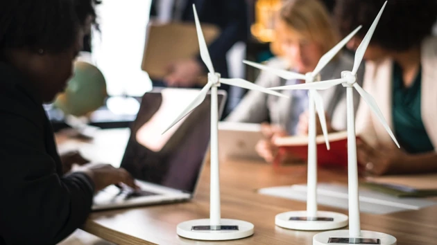 Miniature wind turbines sit on a desk next to computers.